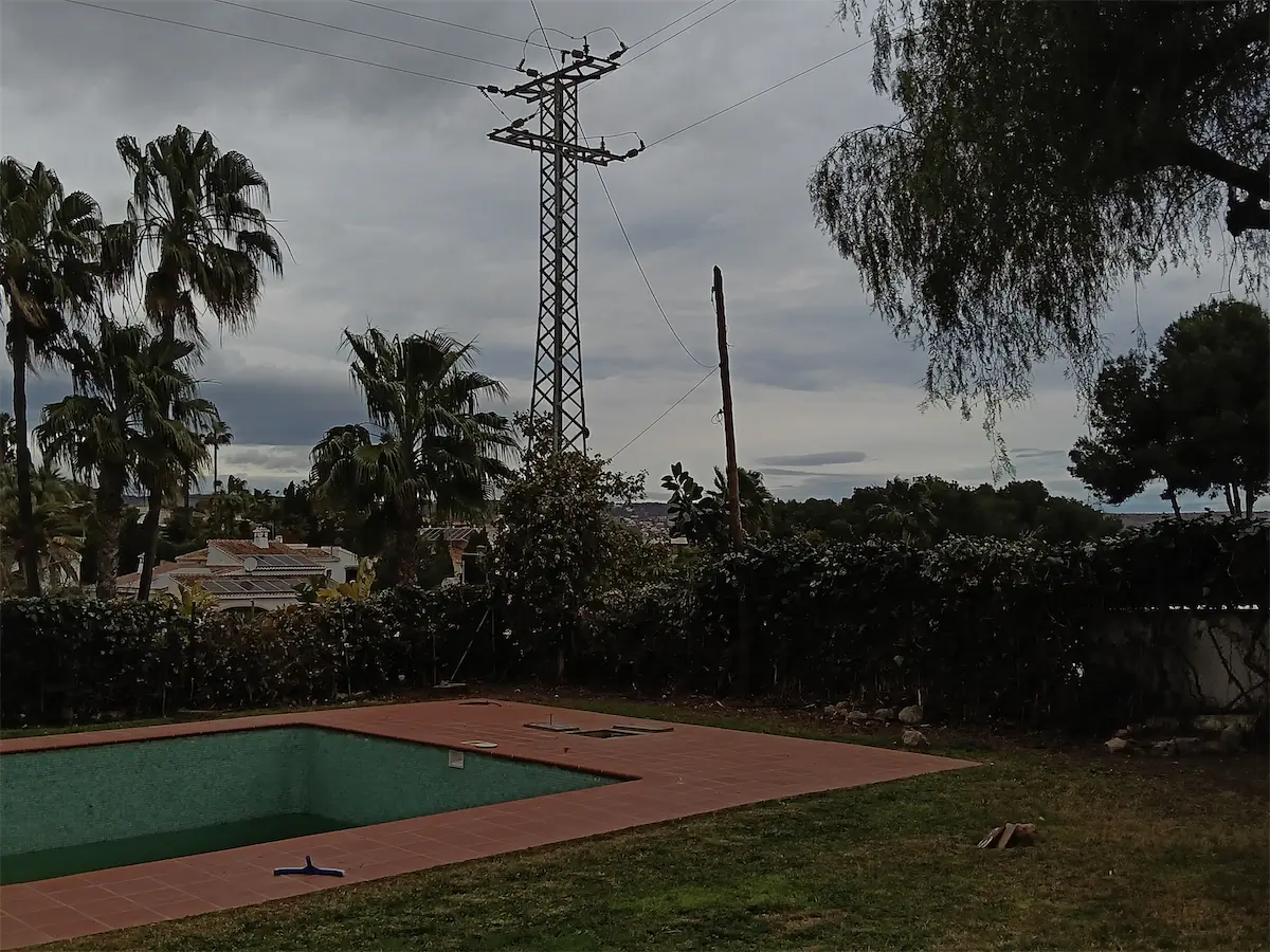El jardín en febrero: piscina con borde de ladrillo, césped seco y setos sin podar