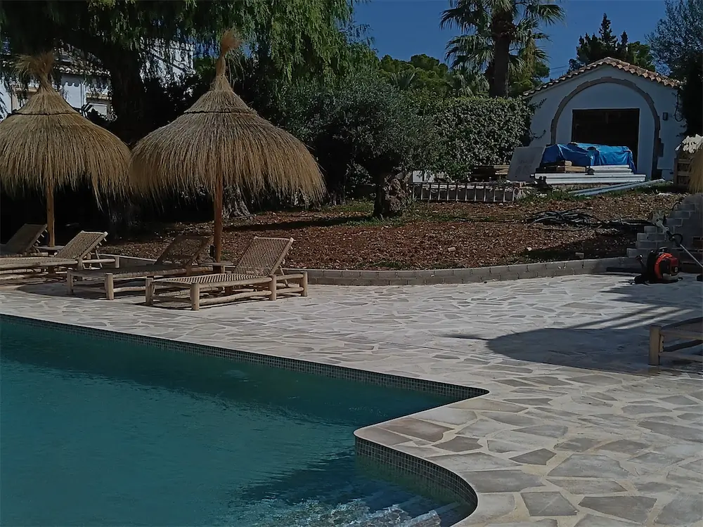 Jardín recién terminado junto a una piscina, con el pavimento nuevo puesto